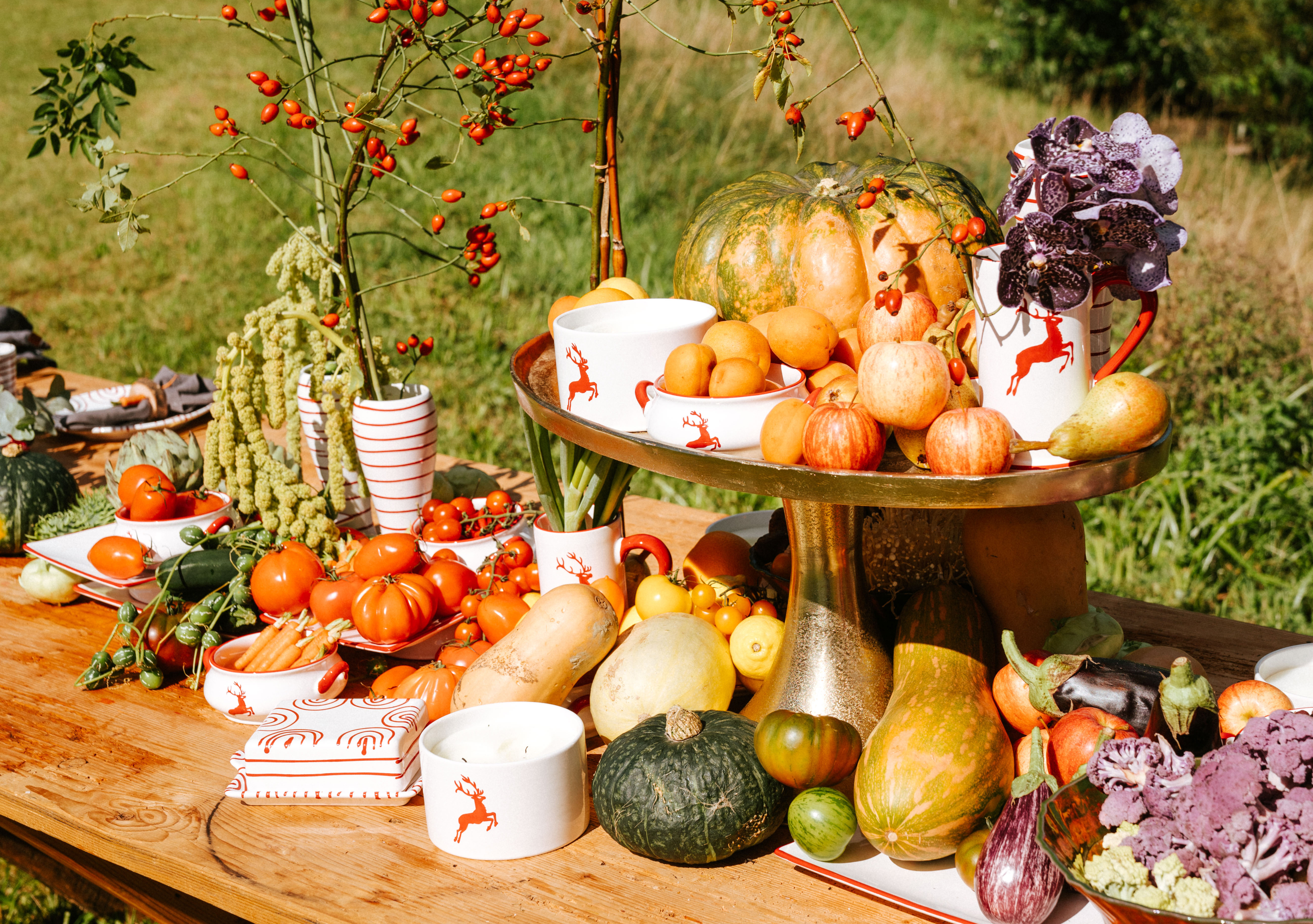 Gedeckter Herbsttisch im freien mit Kürbissen und Gmundner Keramik Geschirr im Design Rubinroter Hirsch