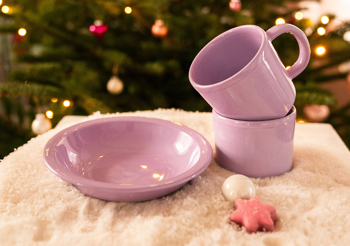 Lilafarbenes Geschirr vor einem Weihnachtsbaum