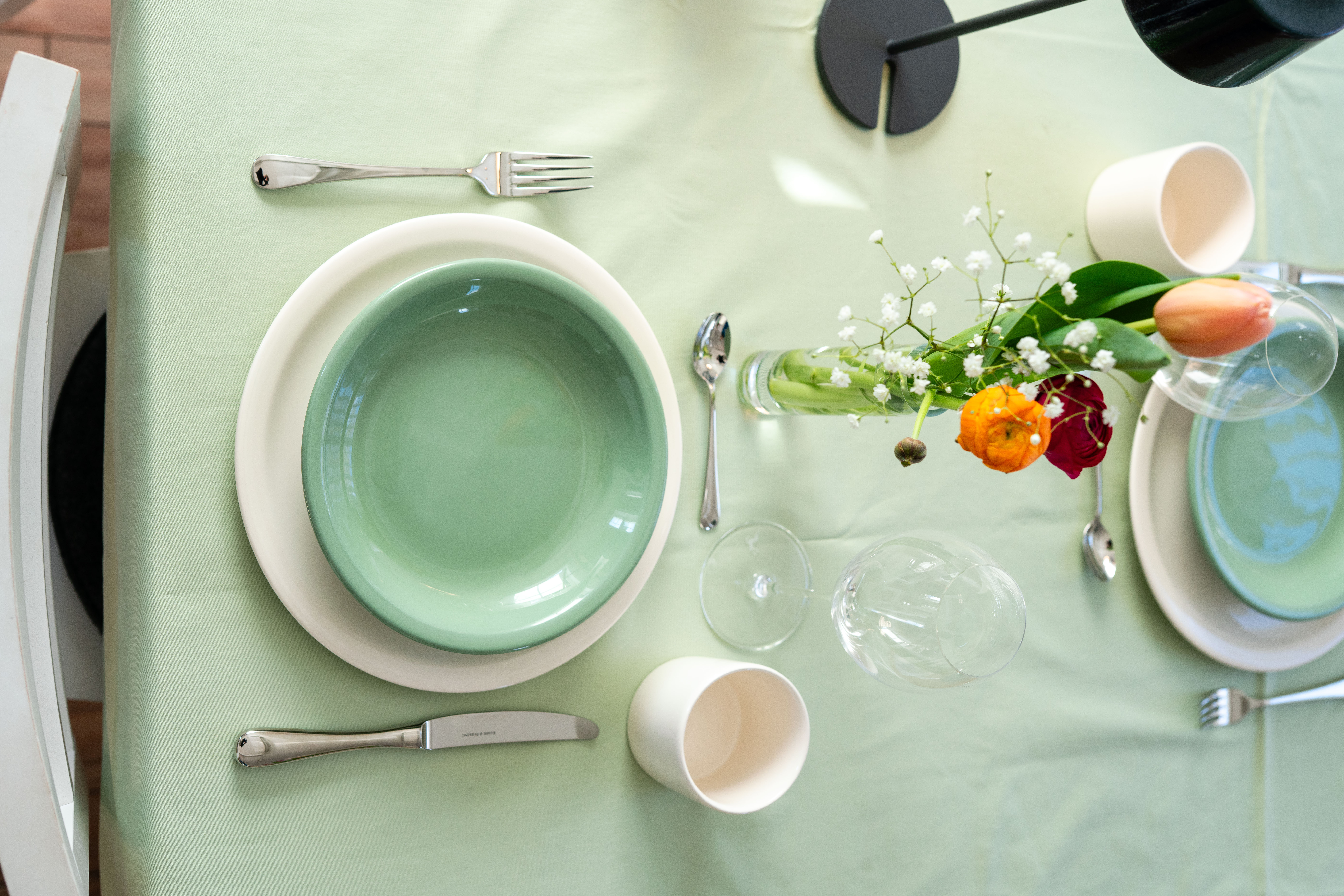 Gedeckter Tisch mit Schüssel, Teller, Becher und Blumen 