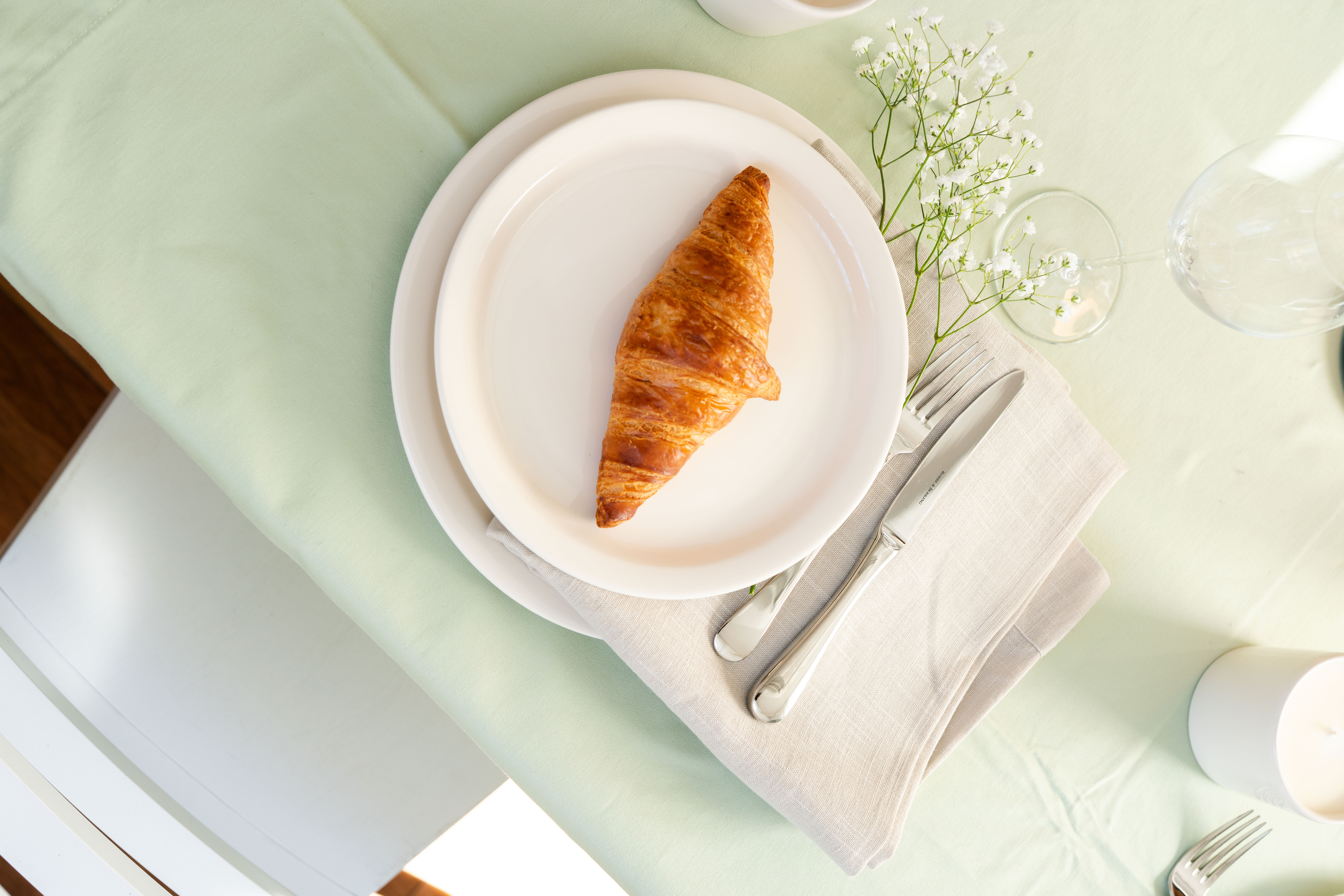 2 Teller auf einem grünen Gedeckten Tisch, mit einem Croissant darauf