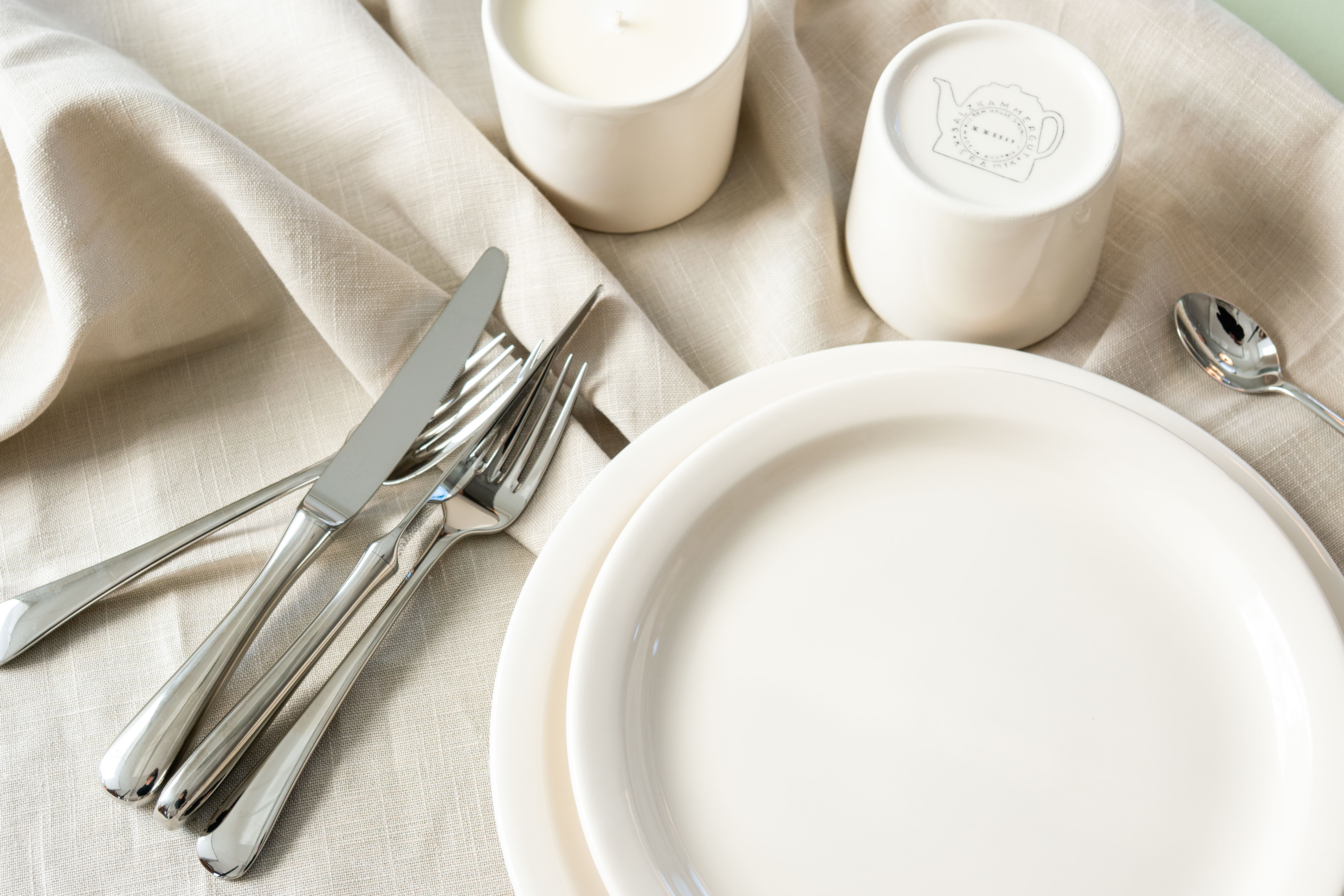 Weiße Teller und Becher auf einem Tuch