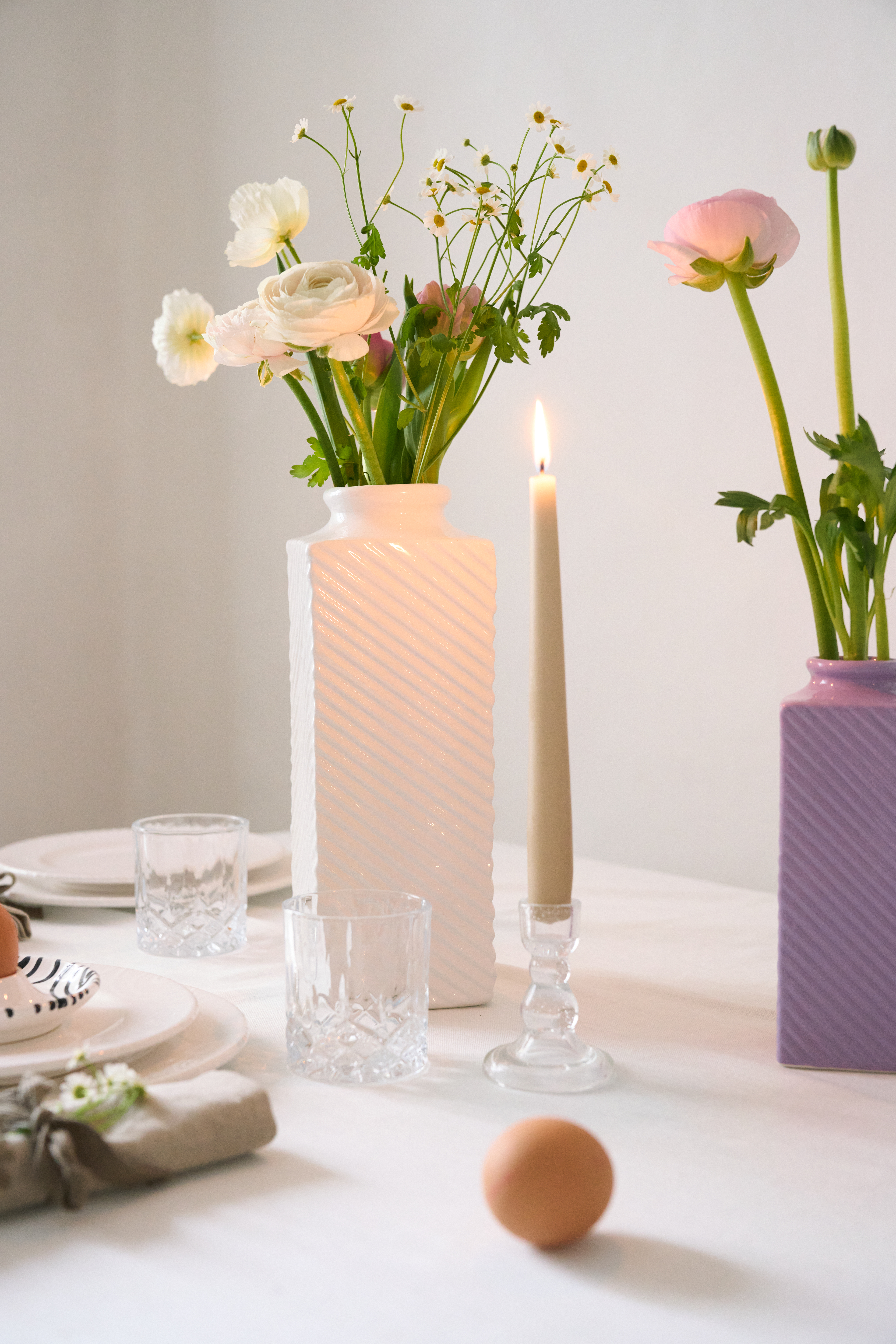 Eine weiße Vase mit Blumen auf einem gedeckten Tisch