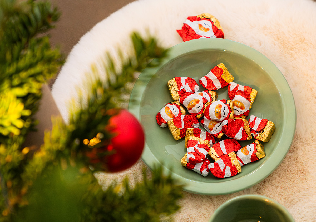 Salbeigrüne Schale vor einem Christbaum mit  Nikoläuse